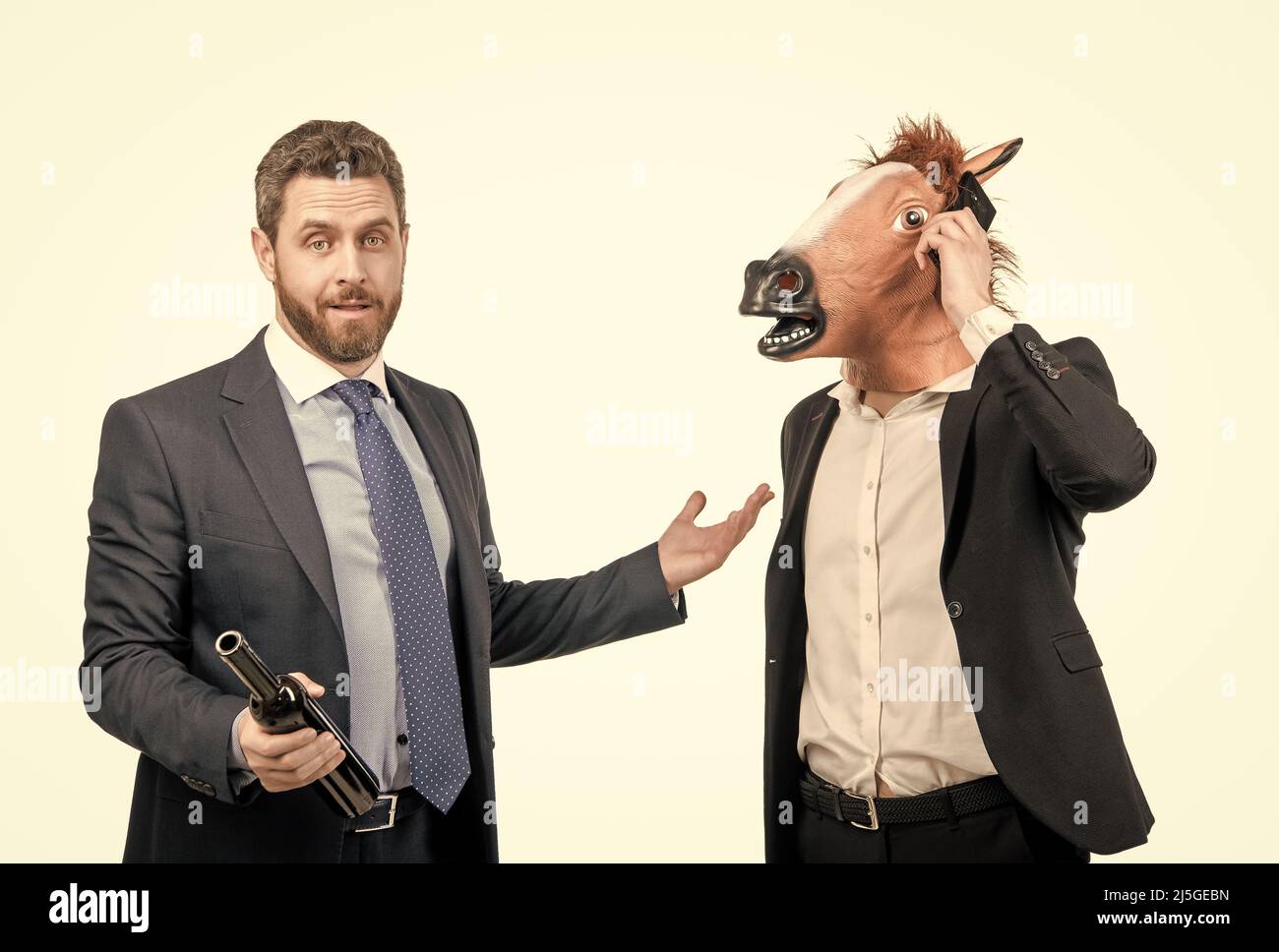 Drunk businessman show at hardworking man in horse head talking on phone on party, workaholic Stock Photo