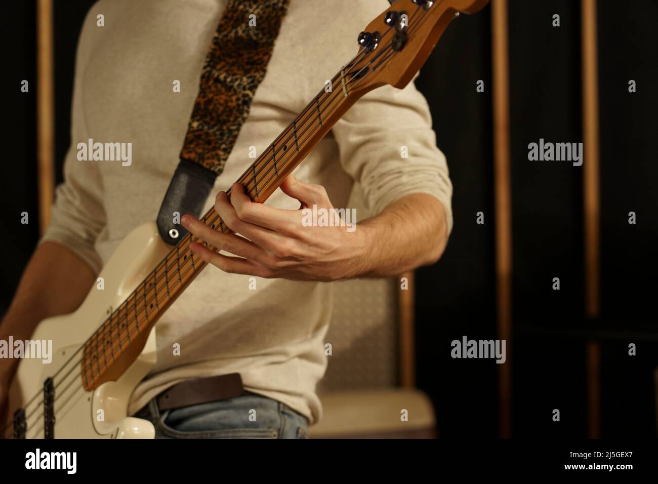 The guy plays the bass guitar. Bass guitarist holds an electric guitar in his hands and plays on it Stock Photo