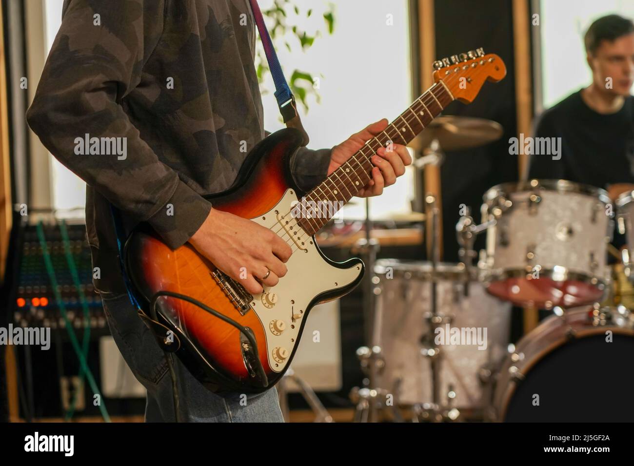 The guy plays the electric guitar to record the sound. He holds a guitar in his hands Stock Photo