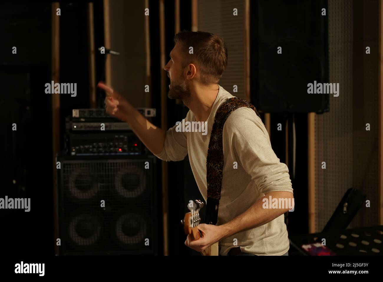 The guy plays the electric guitar to record the sound. He holds a guitar in his hands Stock Photo