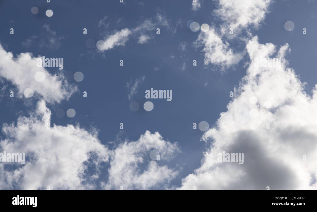 Little white dots in front of lens with blue skies behind Stock Photo