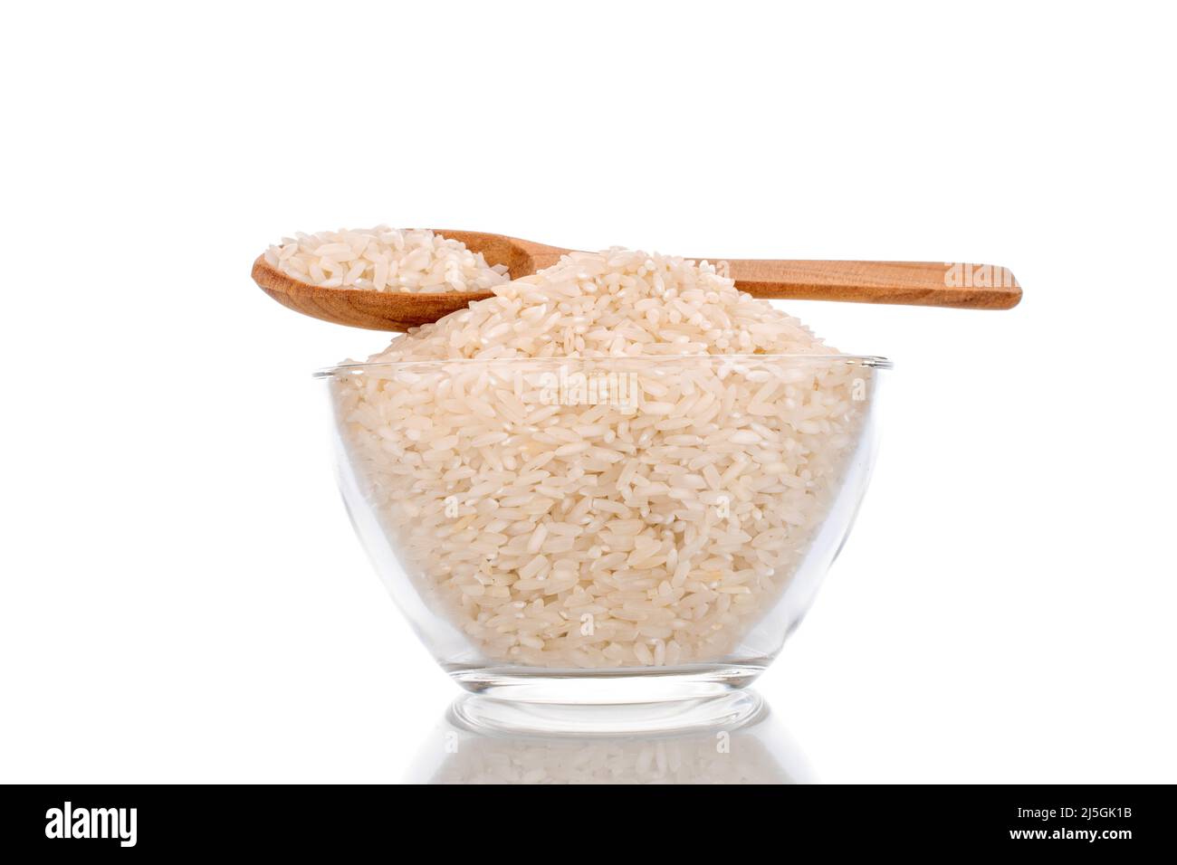 Uncooked organic rice with wooden spoon and glassware, macro, isolated on white background. Stock Photo