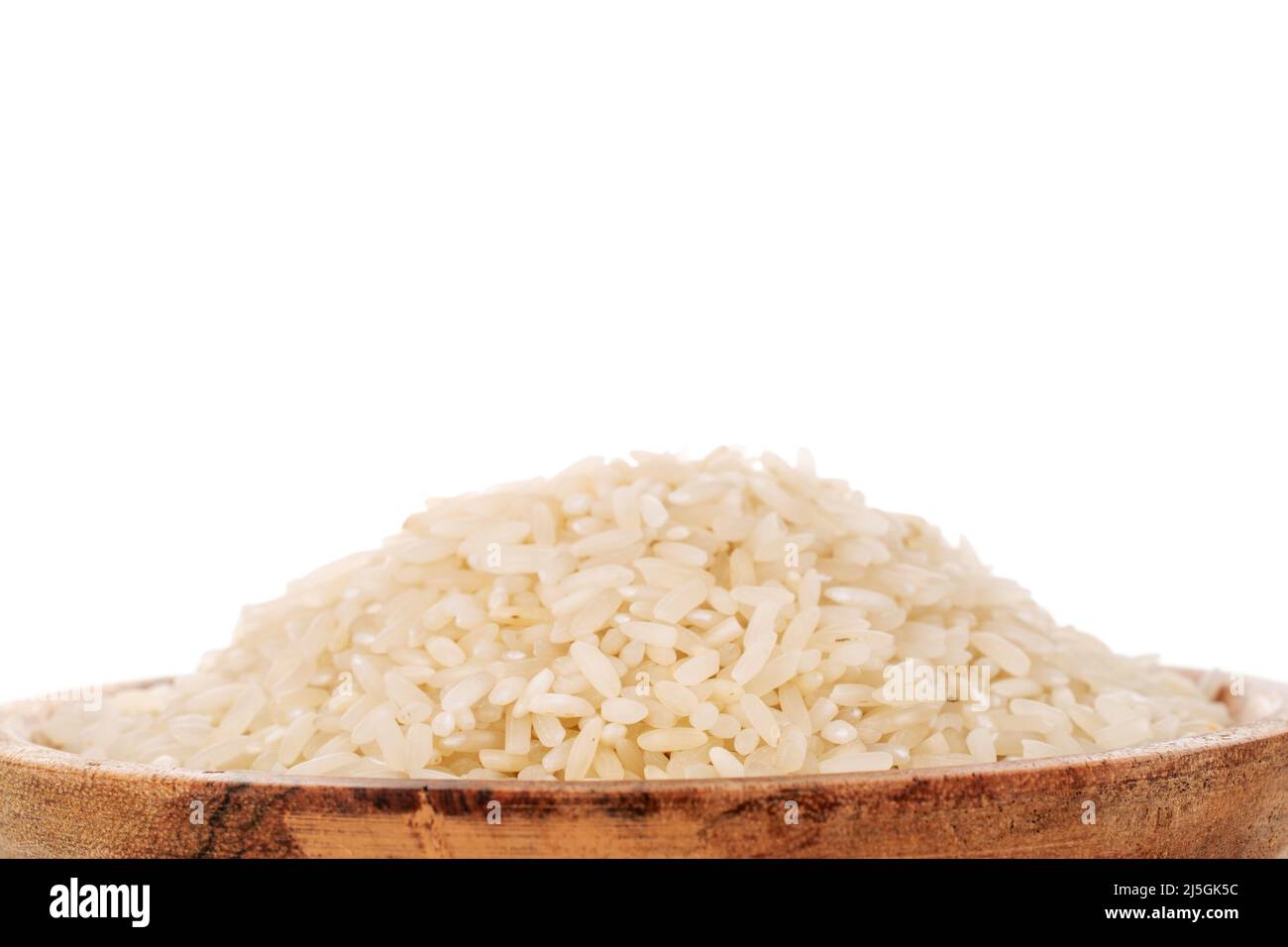 Uncooked organic rice on a wooden plate, macro, isolated on a white background. Stock Photo