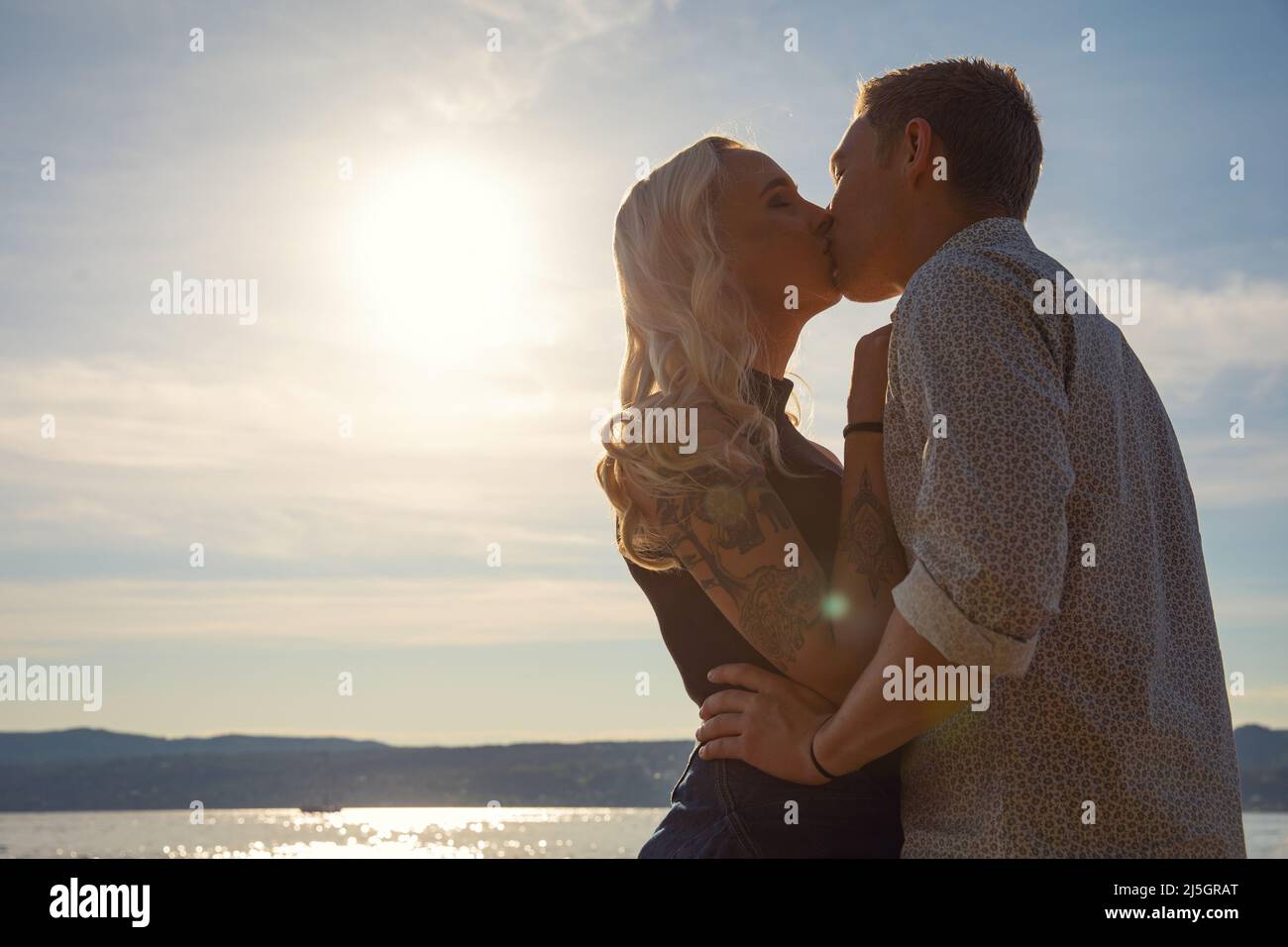 Romantic couple kissing on beach against the sun Stock Photo - Alamy - Kissing Techniques For A Romantic Beach Date