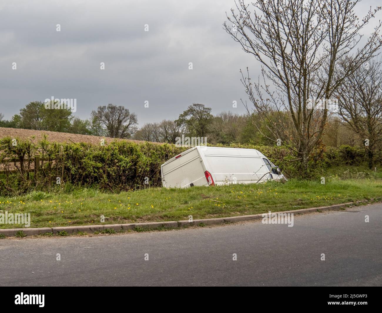 Unidentifiable white van in ditch, abandoned. Stock Photo