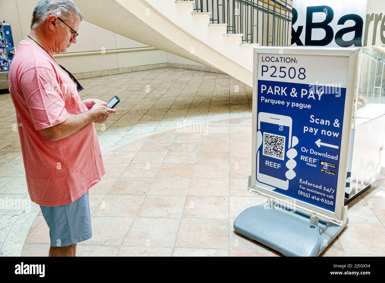 Miami Florida Coral Gables Shops at Merrick Park upscale outdoor shopping mall car park parking garage sign scan pay now QR code Hispanic man smartpho Stock Photo