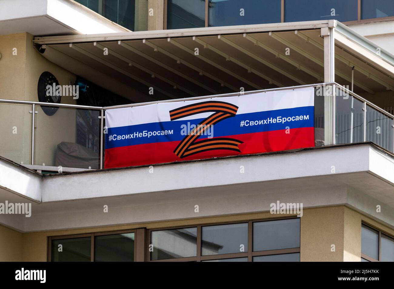 Moscow, Russia. 22th April, 2022. The banner with Russian tricolor and symbol 'Z' is seen on the facade pf the building at the Strastnoy boulevard in central Moscow, Russia. In Russia, the letter 'Z' became a symbol of approval for Russia's military campaign in Ukraine. The banner reads 'We don't abandon our own' Stock Photo