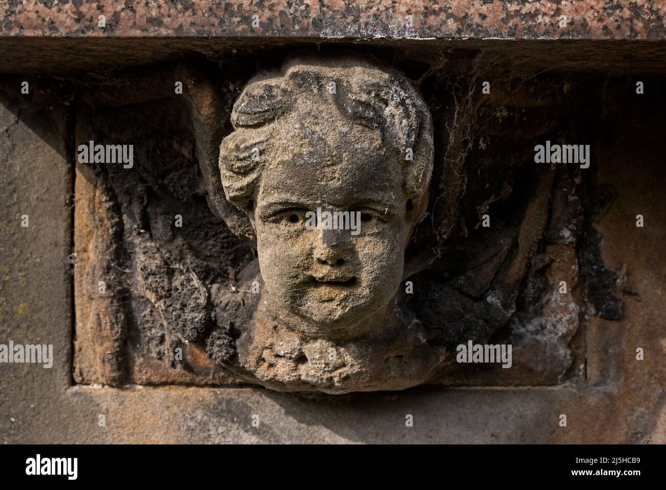 Worn and weather stone head on an 18th century memorial in Canongate Kirkyard on Edinburgh's Royal Mile. Stock Photo