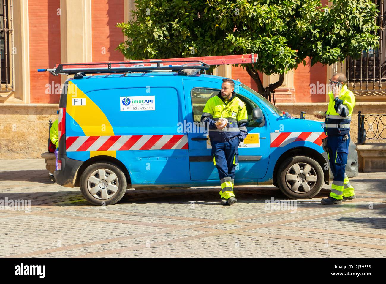 utility workers in hi-vis with imes aPI services and facilities van in Seville Sevilla Spain Stock Photo