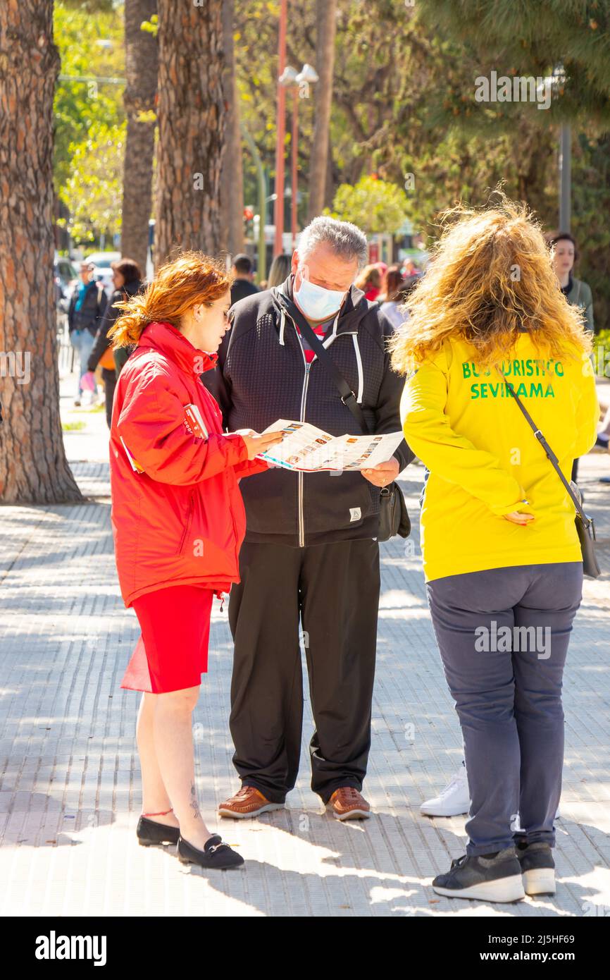 tourist wearing mask discuss map of city bus tour with guide in Seville