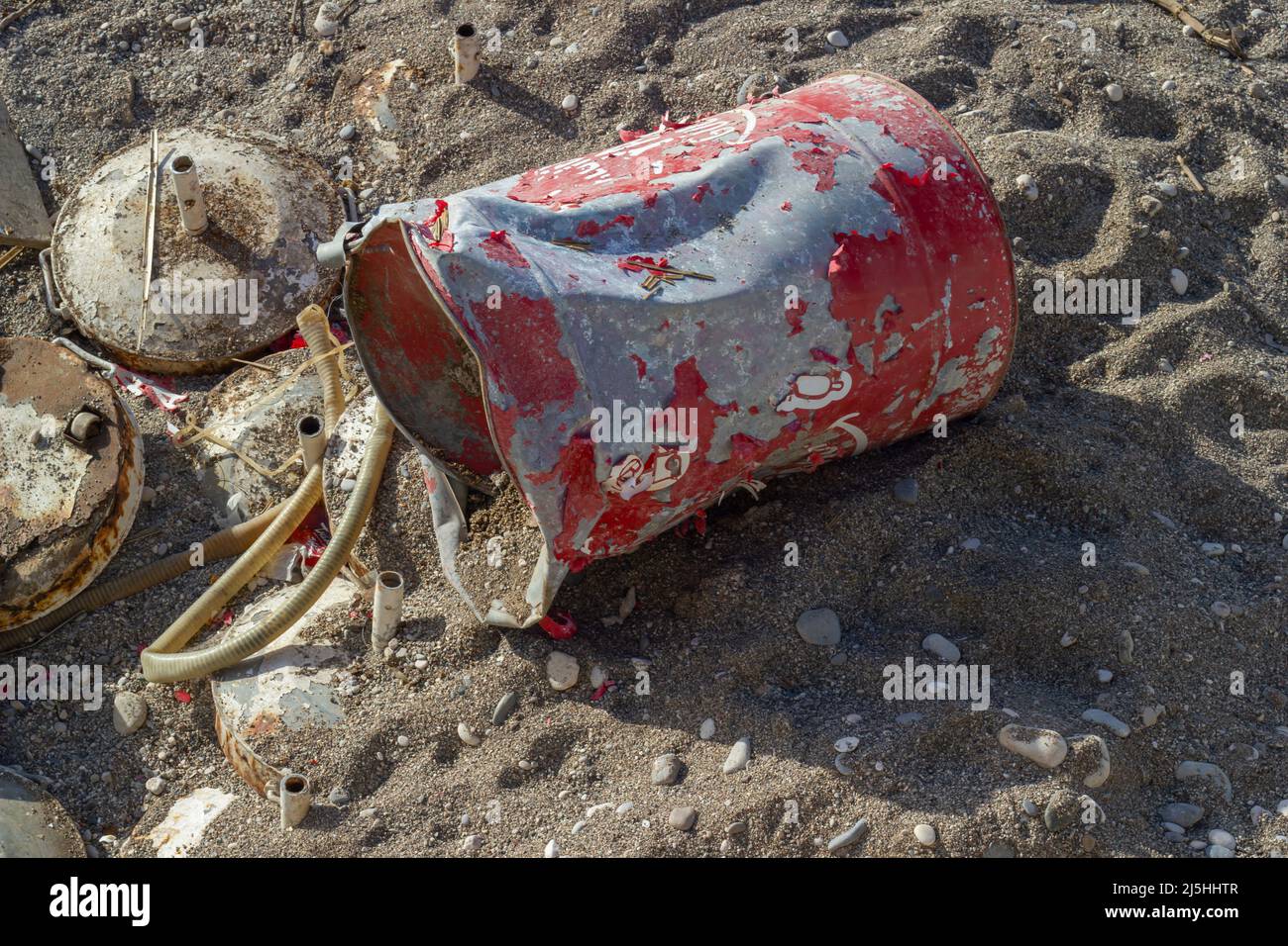Rusty barrel thrown on the beach, hose, garbage, environmental pollution,  trashes in nature. Stock Photo