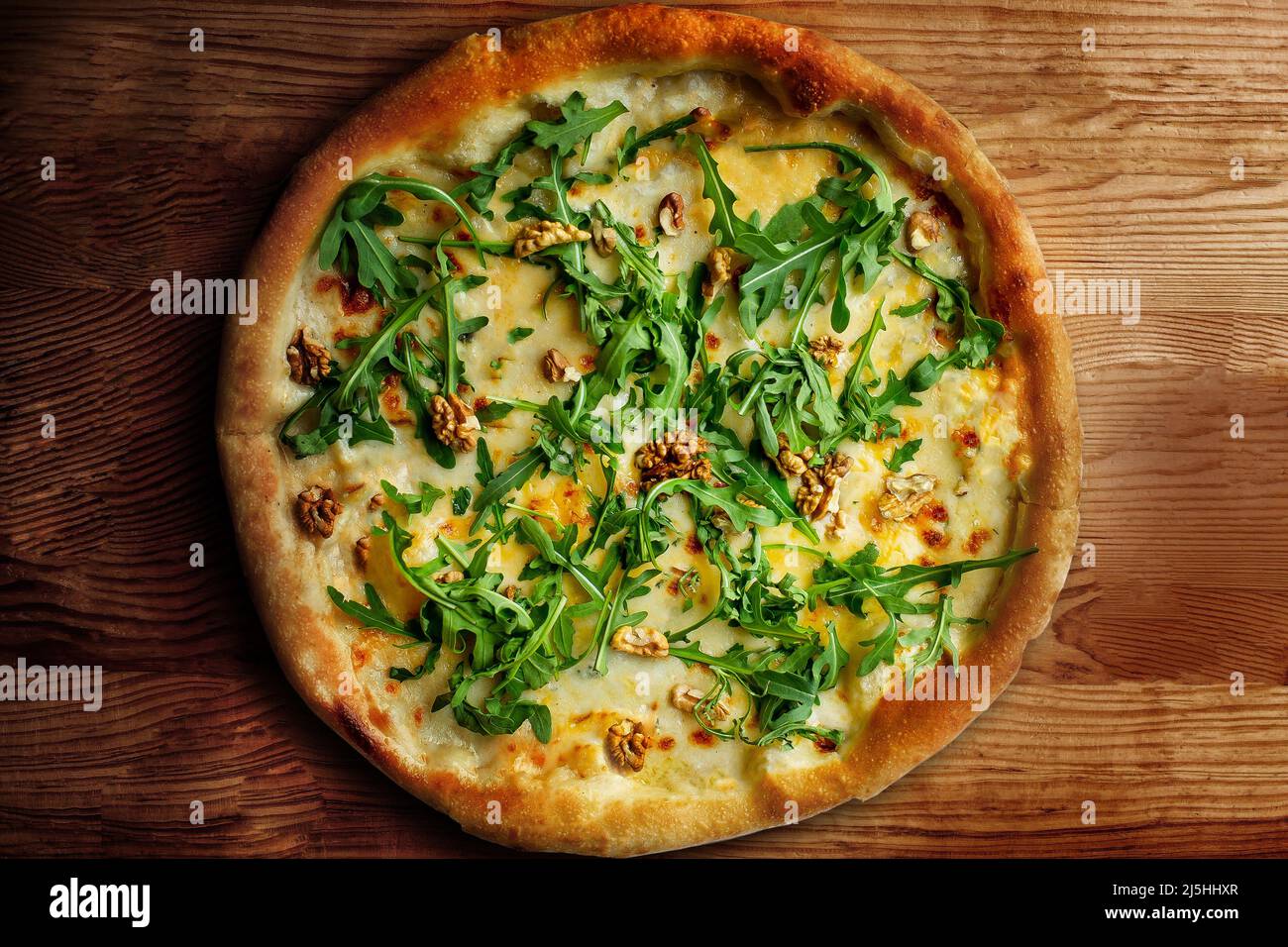 Delicious vegeterian cheese pizza with walnuts and basil wooden table background, closeup top view Stock Photo