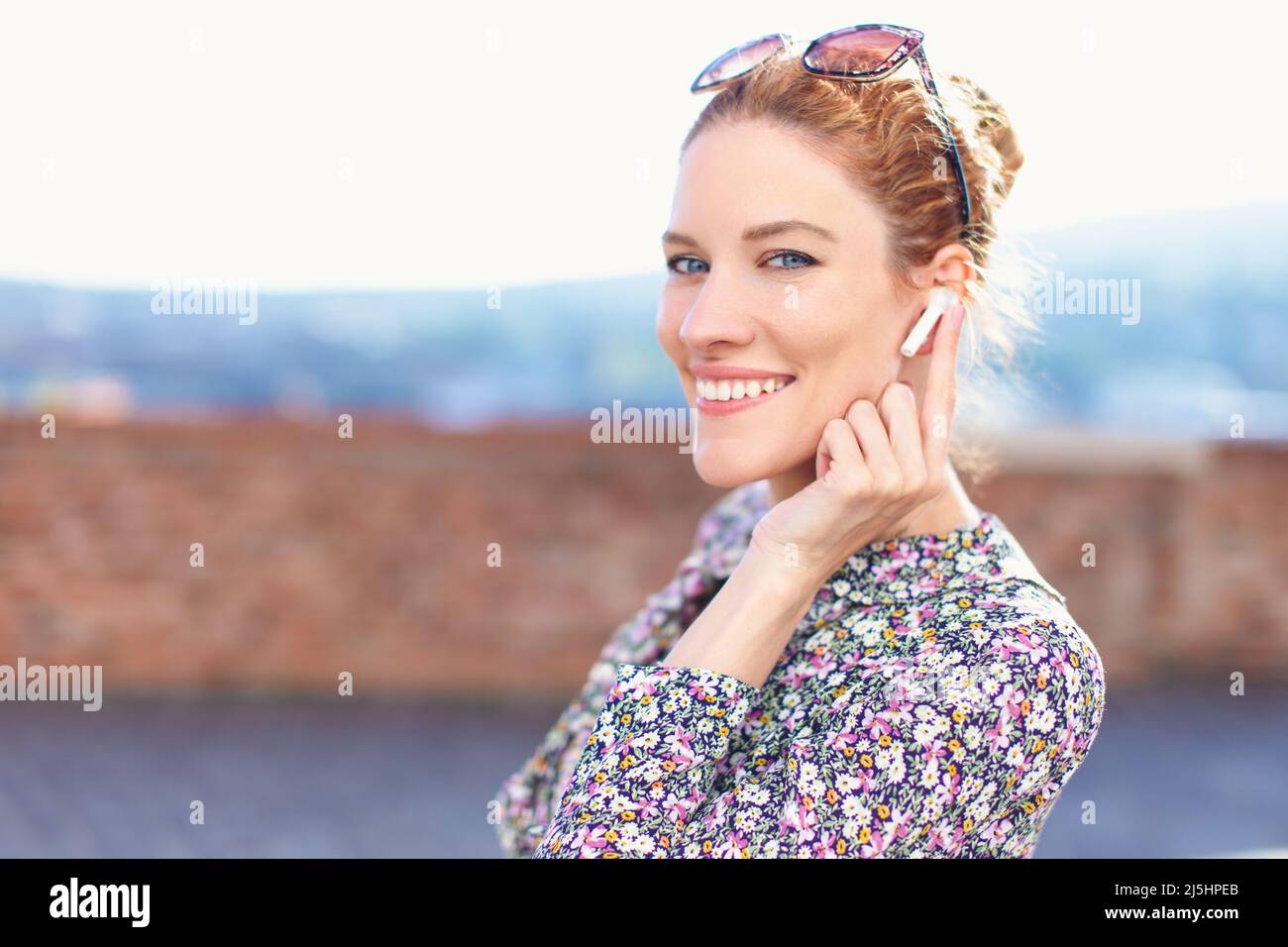 Happy young confident woman with hands free device toothy smiling while listening call Stock Photo