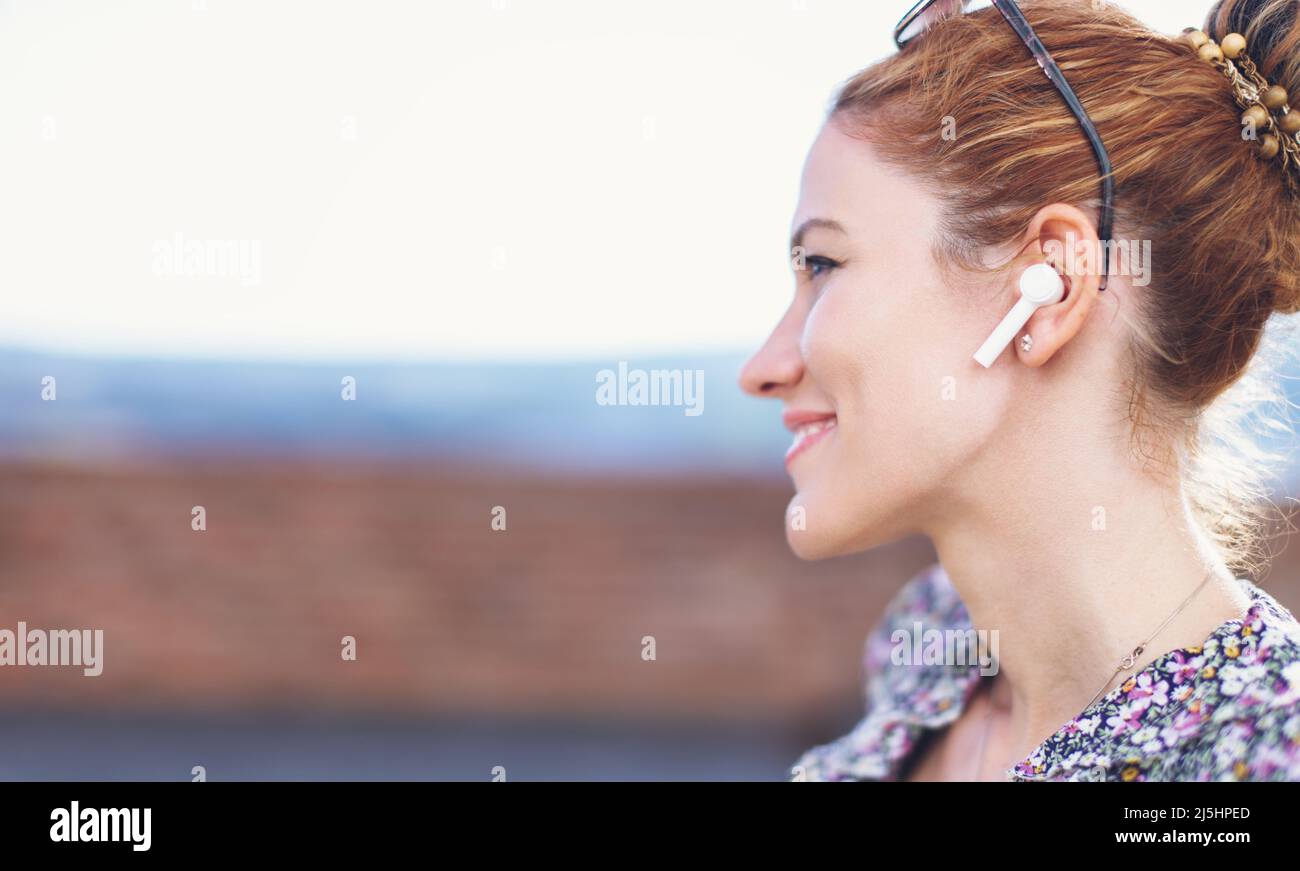 Young redhead woman with hands free device profile view, empty space Stock Photo