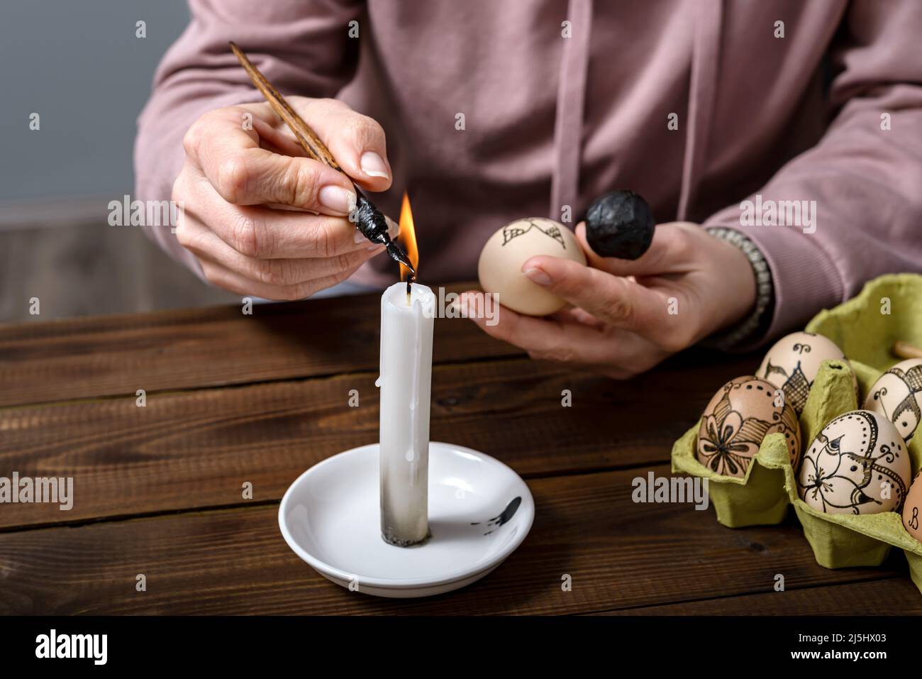 Female hands traditionally paint eggs with floral patterns using a