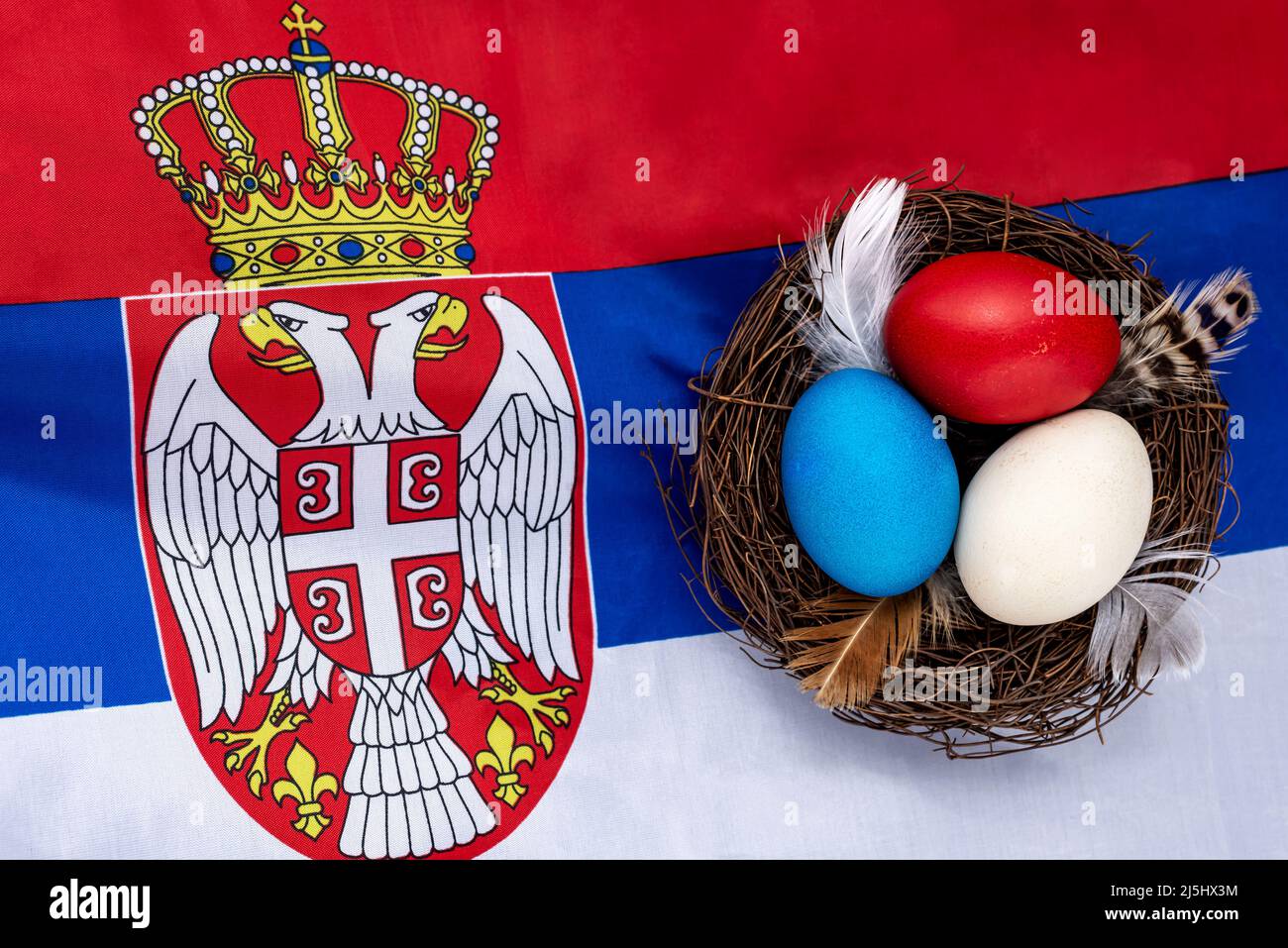 Multicolored decorated Easter eggs in a nest on the flag of Serbia. Easter concept. Stock Photo