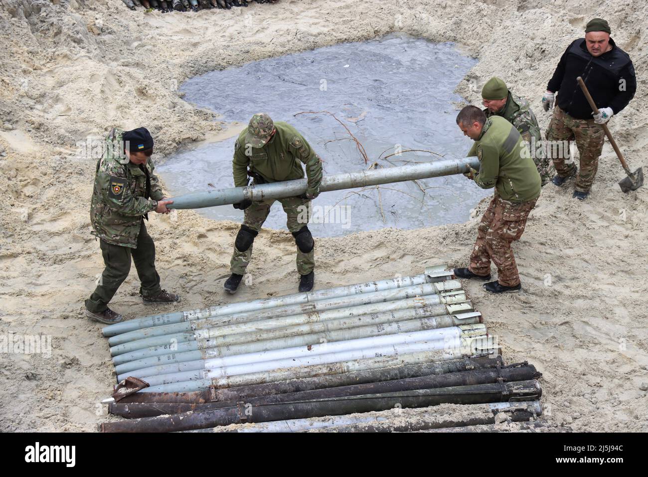 Servicemen arrange the shells on the ground as they work to dispose of