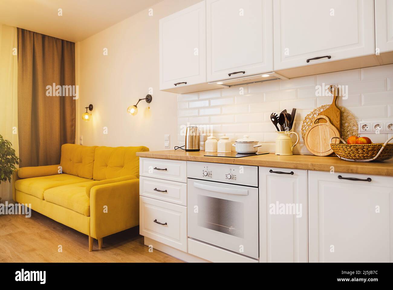 small studio apartment with yellow sofa white kitchen. Cozy light