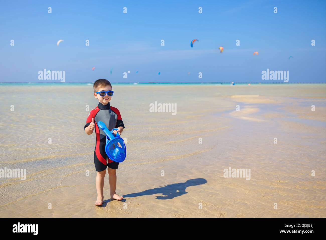 little boy in wetsuit holding snorkeling mask Stock Photo