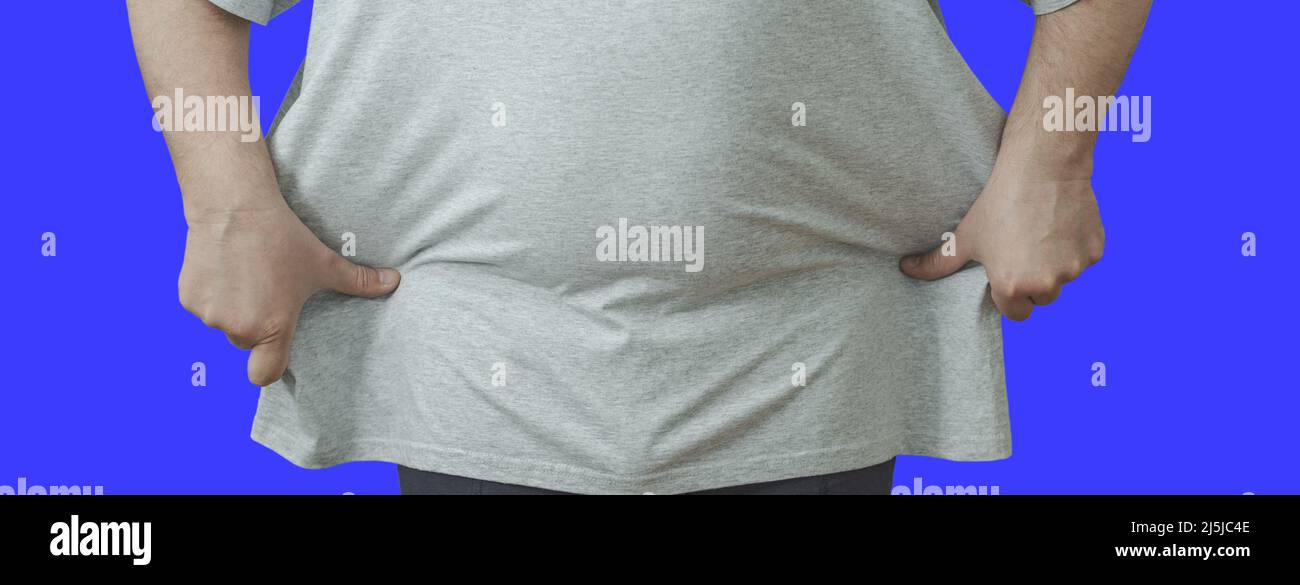 A fat man pulls a tank top on his stomach, the concept of losing weight, healthy eating, playing sports. Isolate. Stock Photo
