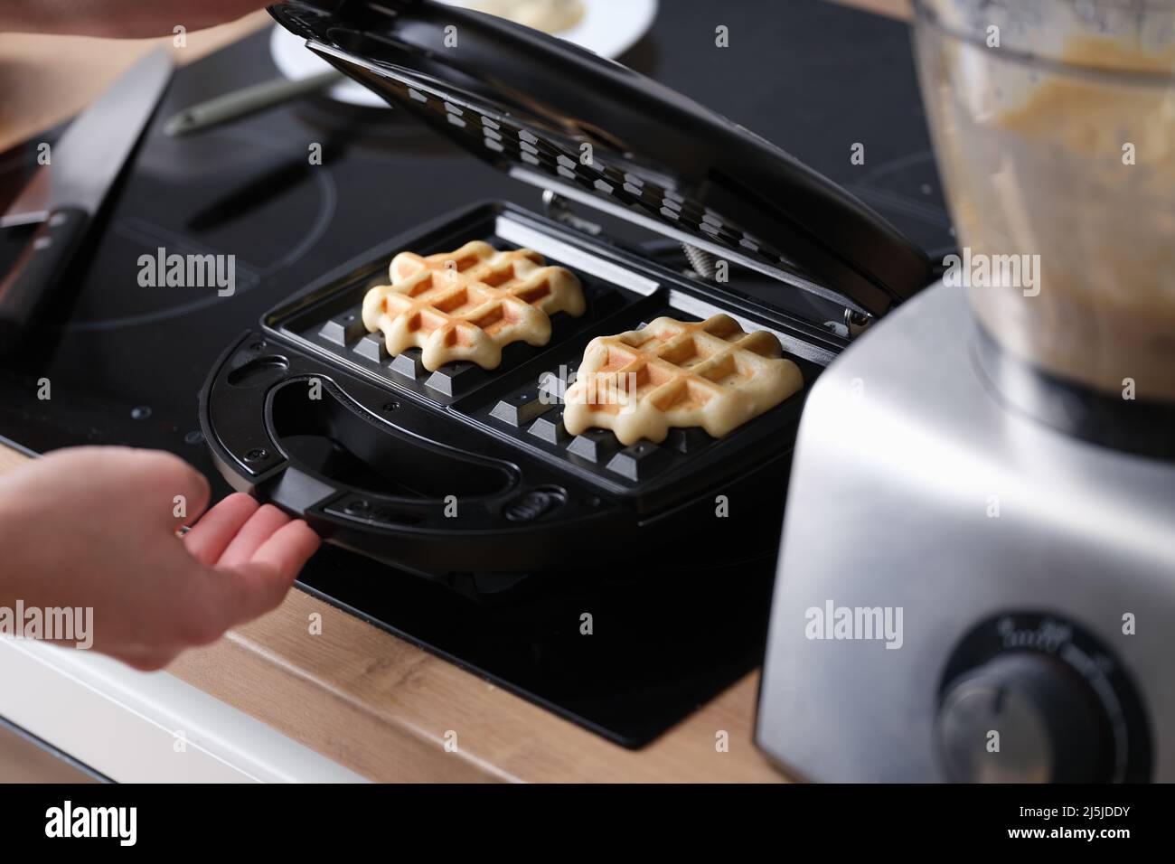 Cooking waffles in waffle iron at home closeup Stock Photo - Alamy