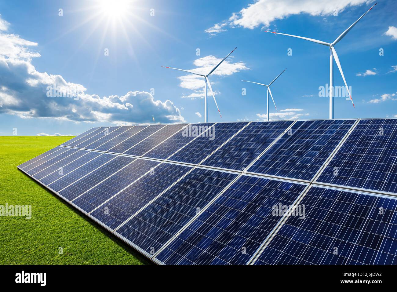 Solar panels and wind turbines with green grass landscape under blue ...
