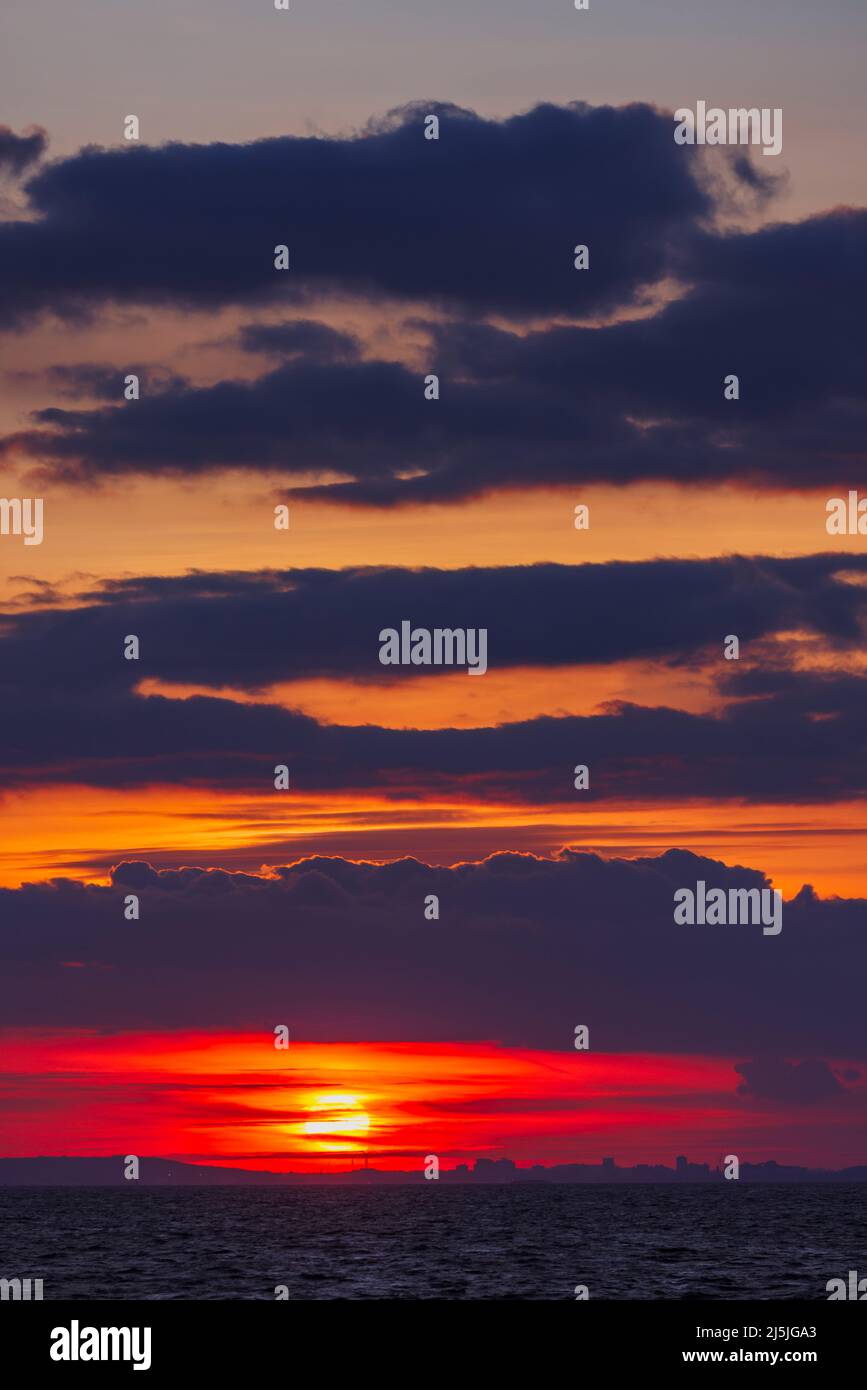 The setting sun lighting up the sky with a reddish orangey glow Stock