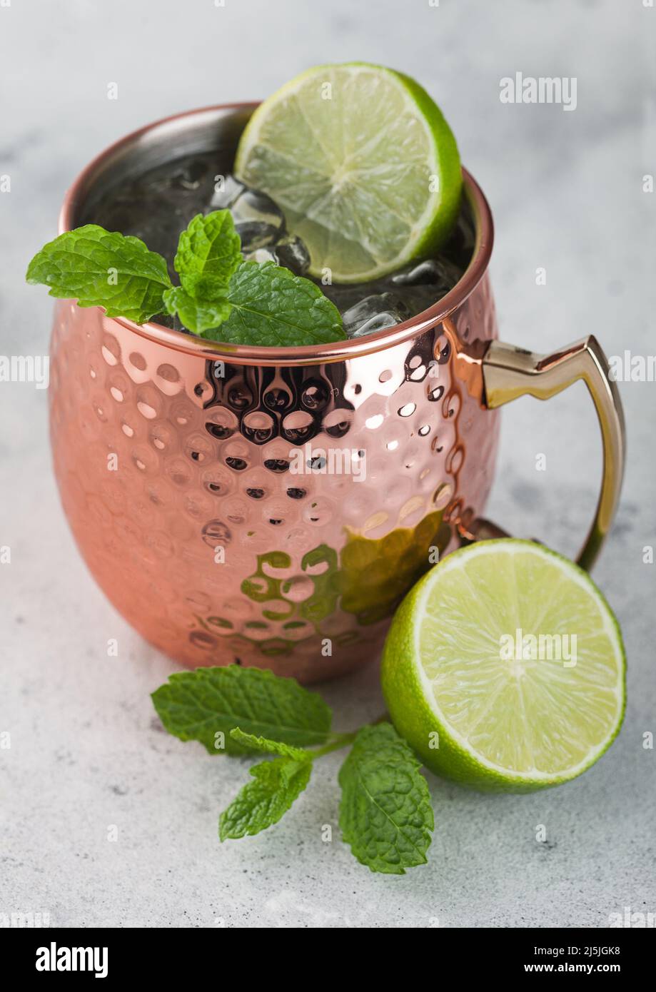 Moscow mule cocktail in a copper mug with lime and mint on light