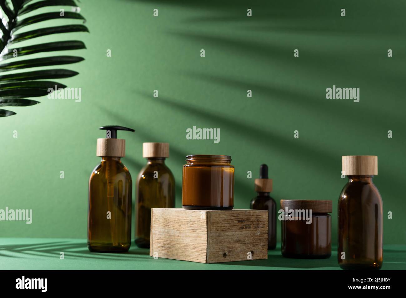 Bottles for cosmetics and cream on a pedestal, green background with ...