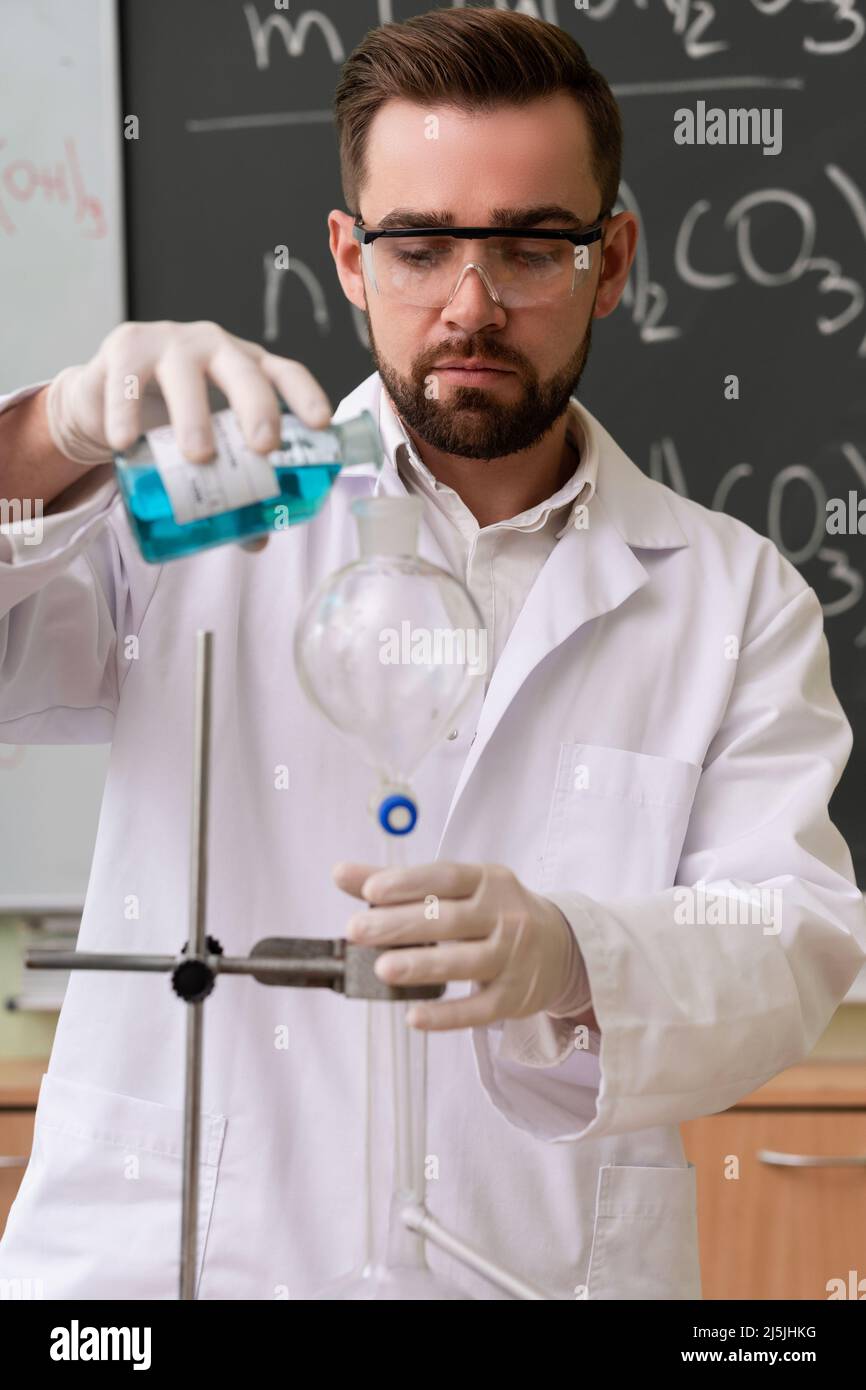 Scientist is pouring substance into the condenser in a laboratory