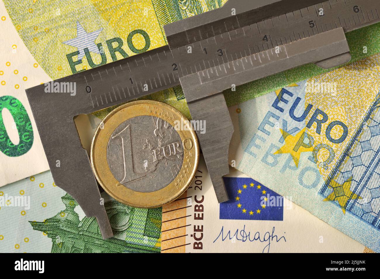Vernier caliper with euro coin on euro banknotes background - Concept of economy and financial evaluation Stock Photo