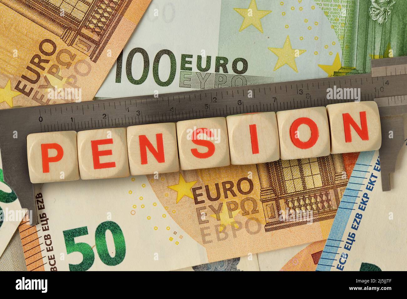 Vernier caliper and wooden blocks with the word Pension on euro money background - Concept of calculating pension Stock Photo