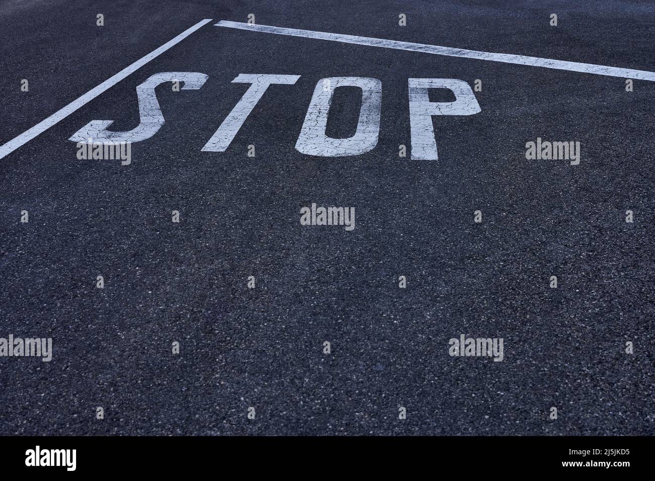 detail of a white stop sign painted on the pavement Stock Photo