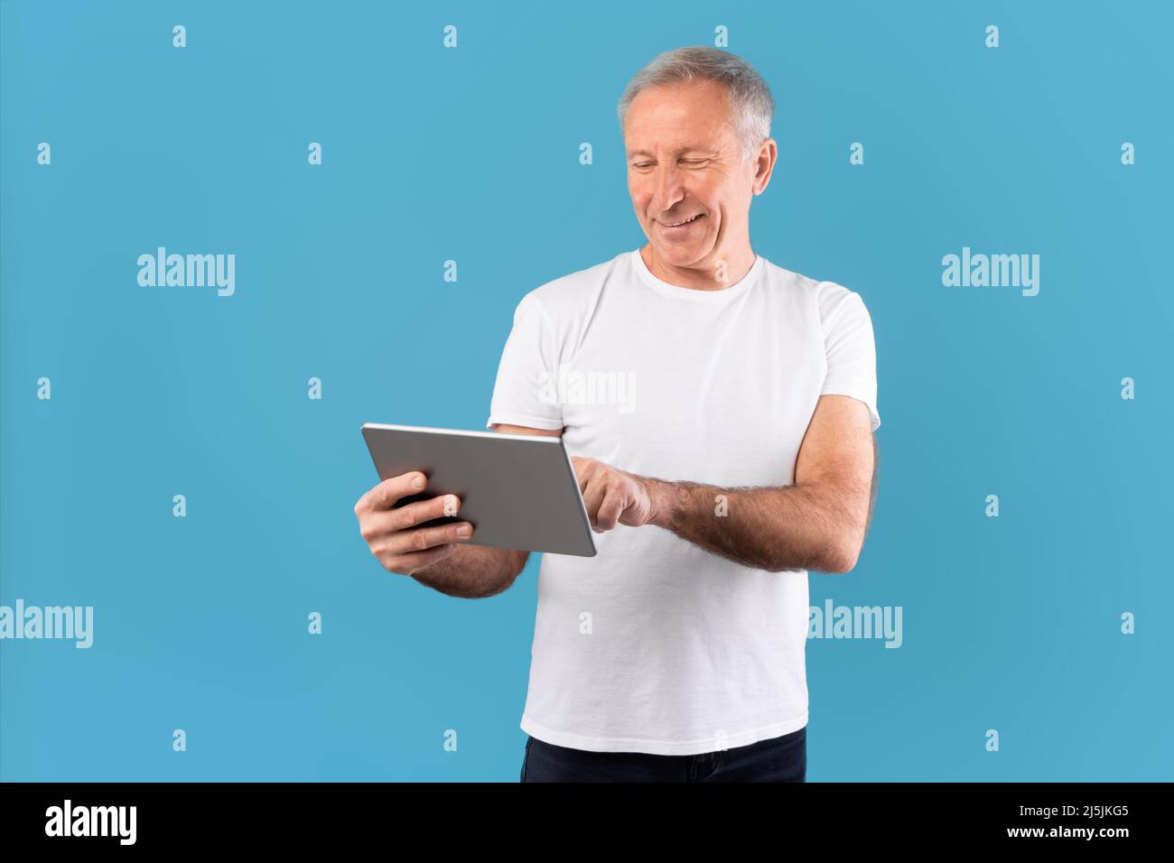 Confident mature man holding and using tablet Stock Photo