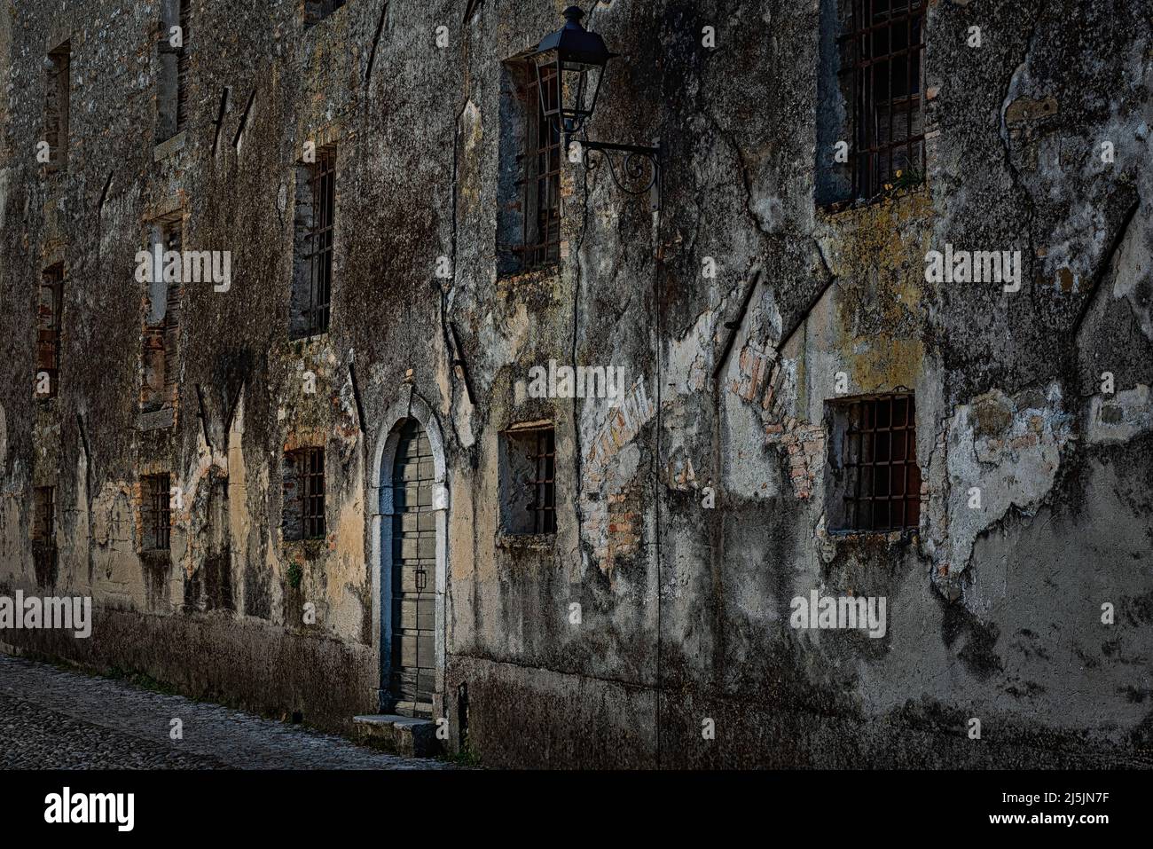 Mystery house facade with rusty iron gratings at the windows. Strassoldo, Udine, Friuli Venezia Giulia, Italy. Stock Photo
