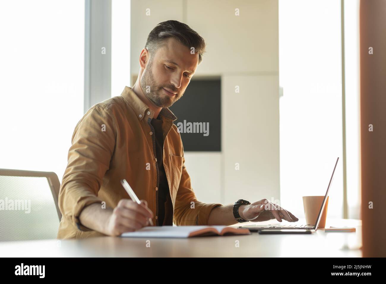 Entrepreneur Man Taking Notes And Using Laptop Sitting In Office Stock ...