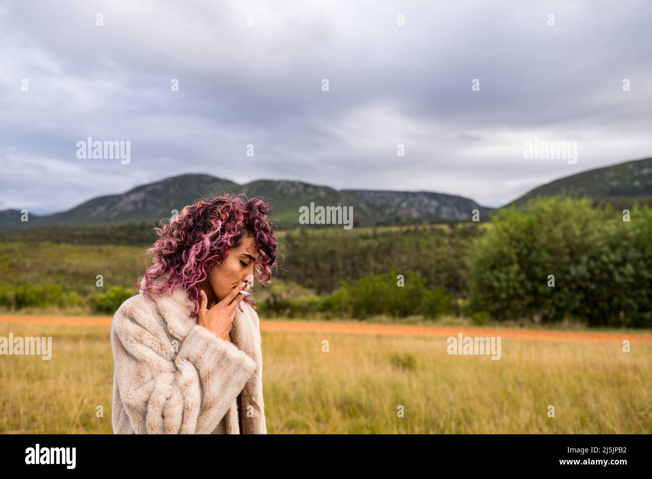 Woman seen smoking a cigarette in nature Stock Photo
