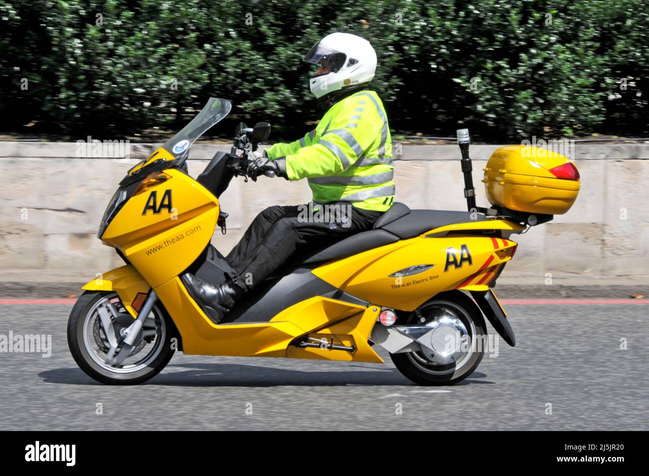 Side view AA patrolman high visibility jacket riding yellow electric scooter bike give members road assistance in congested London streets England UK Stock Photo