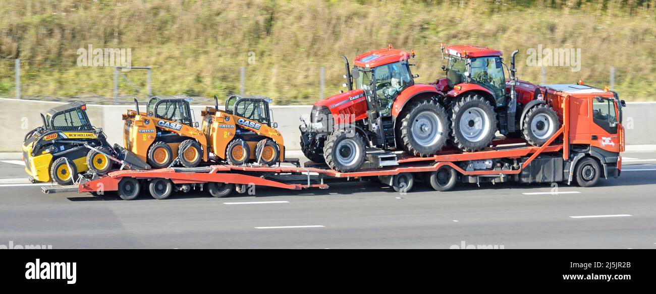 Side view of hgv lorry truck adjustable load platform loaded with two new Case brand of farm tractor & three Skid Steer Loader machines on UK motorway Stock Photo