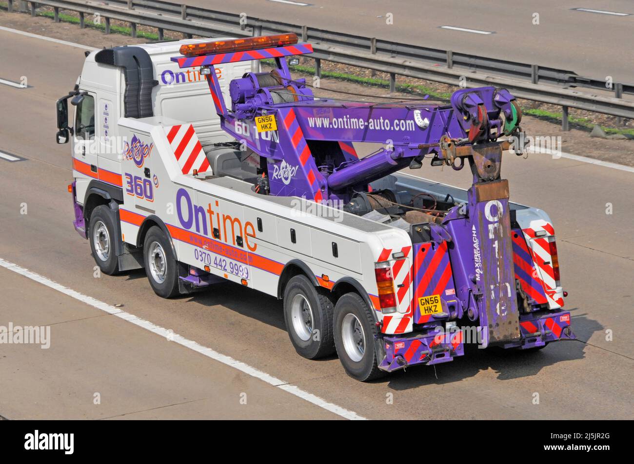 Aerial back rear & side view of colourful Ontime auto hgv heavy lifting breakdown recovery lorry truck vehicle driving along motorway road England UK Stock Photo