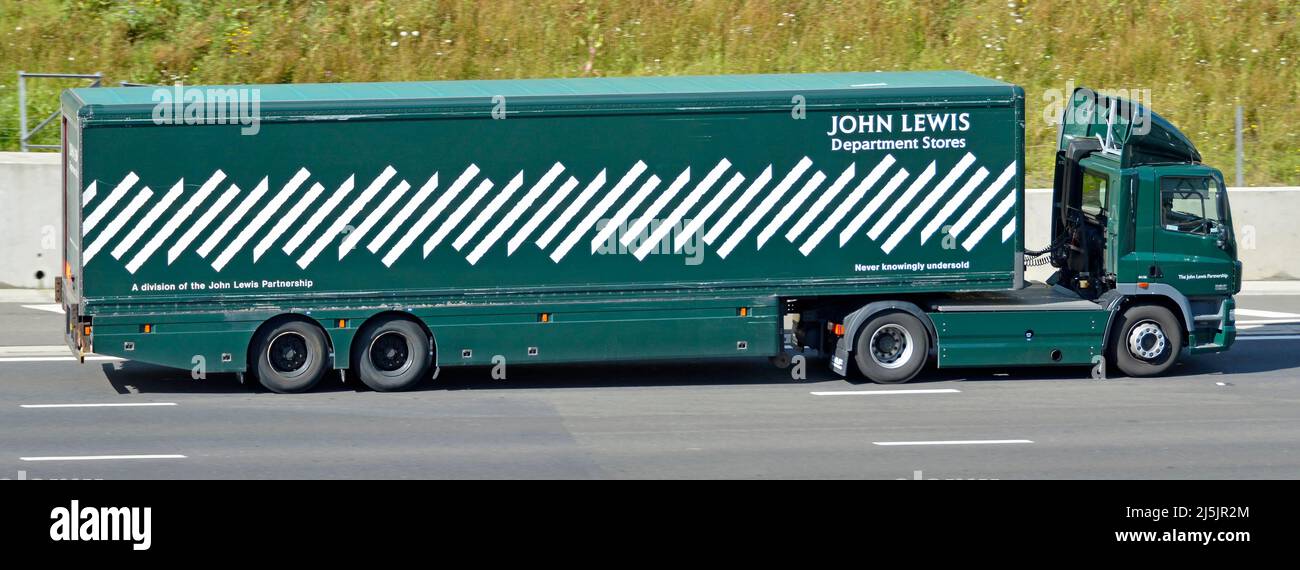 Side view of John Lewis department store long lorry truck advertising brand name logo on store delivery supply chain trailer driving UK motorway road Stock Photo