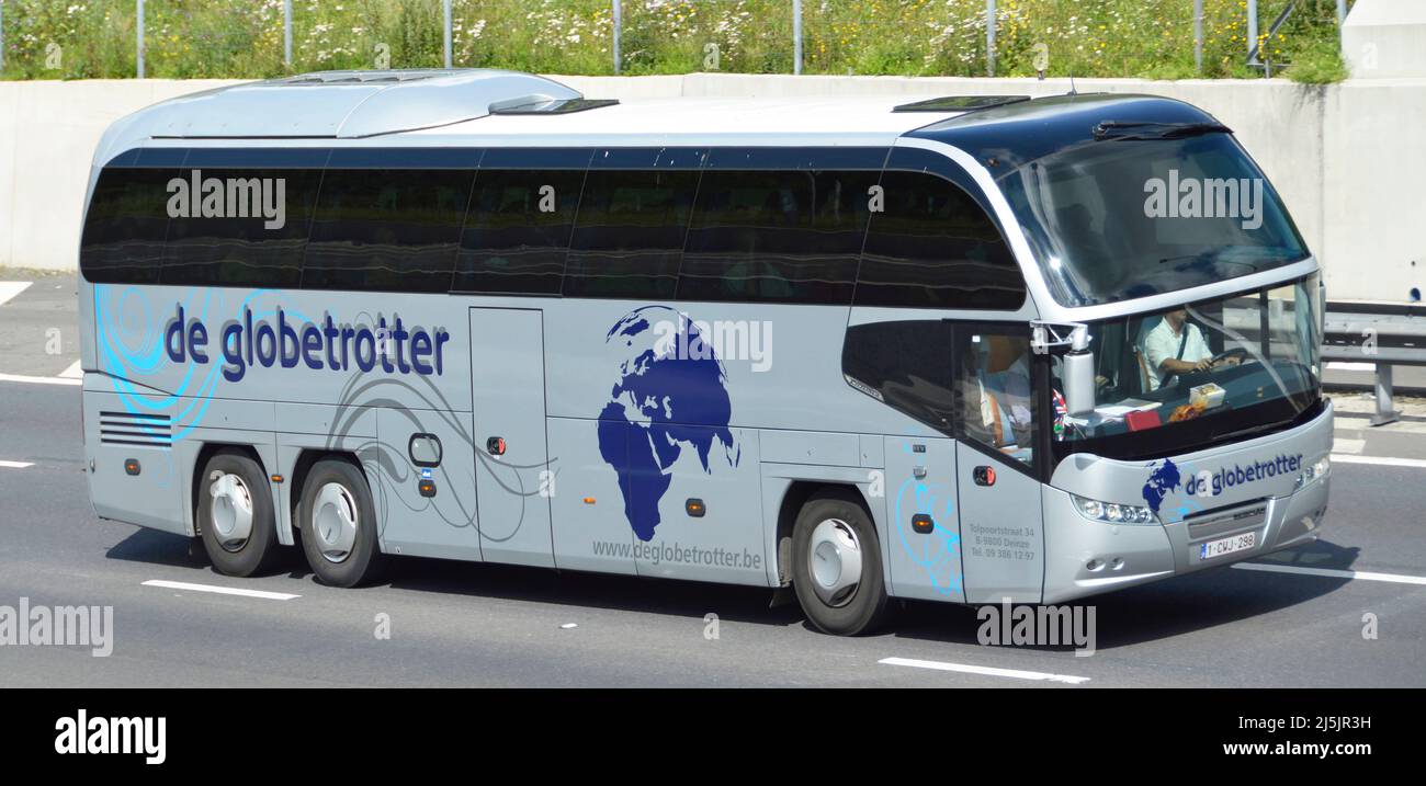 Side and front view of De globetrotter holiday coach and bus operator & driver business from Belgium tinted glass windows driving on UK motorway road Stock Photo