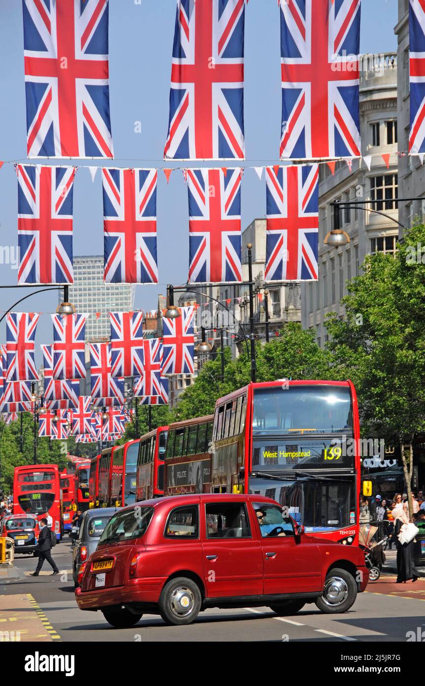 Taxi cab U turn in Oxford Street West End London Union Jack flags for Queens Jubilee & 2012 Olympics Paralympic Games red bus traffic queue England UK Stock Photo
