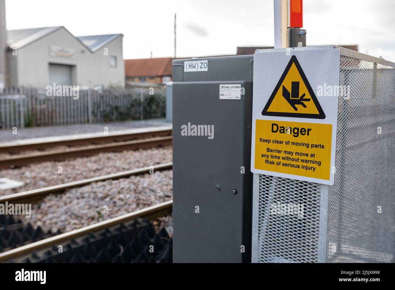 Warning sign to inform the public to keep clear from the moving barrier as there is a risk of injury Stock Photo
