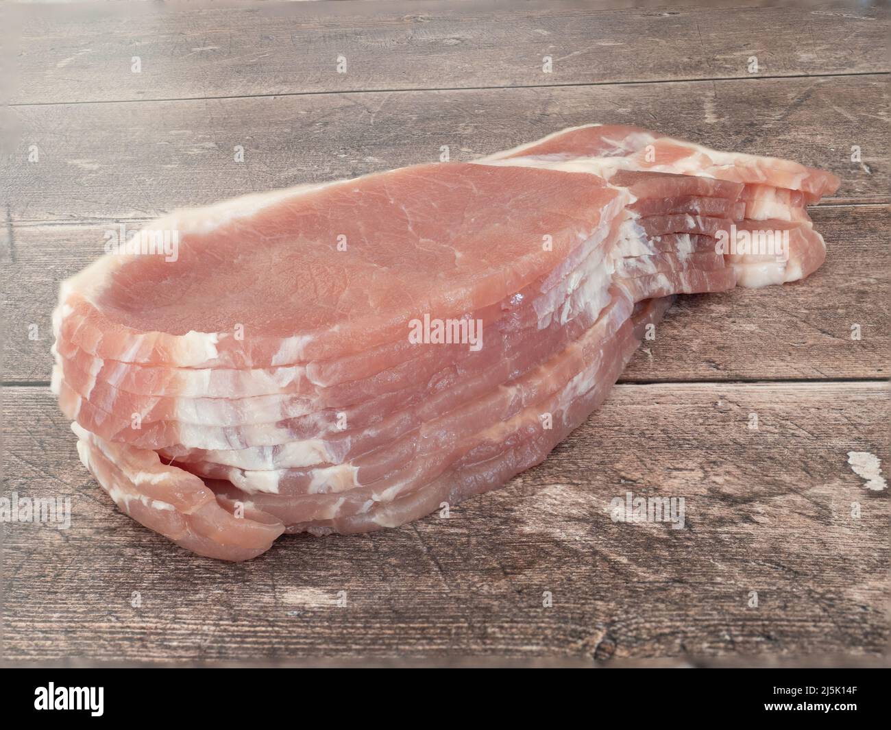 Slices of raw back bacon on a wooden table Stock Photo