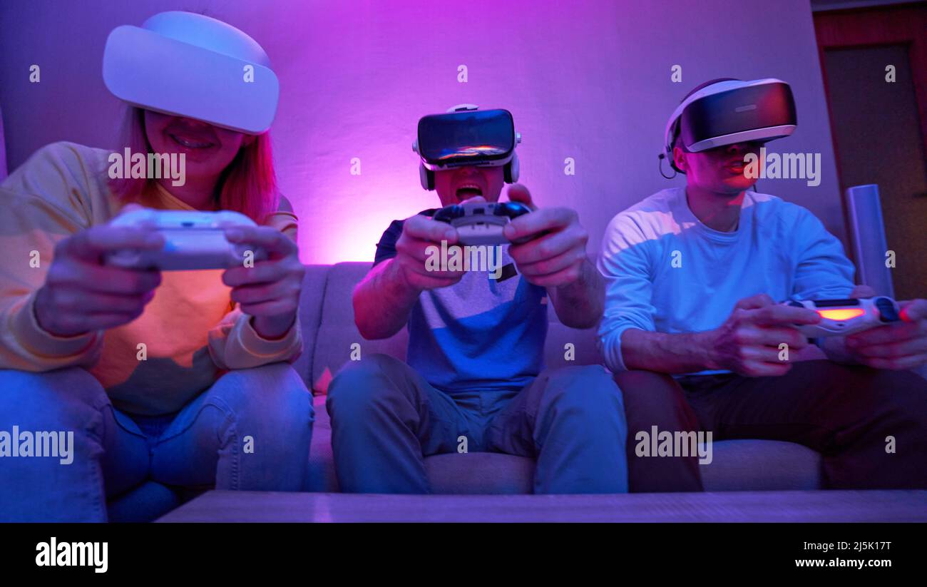 Friends playing virtual reality games using joysticks while sitting on