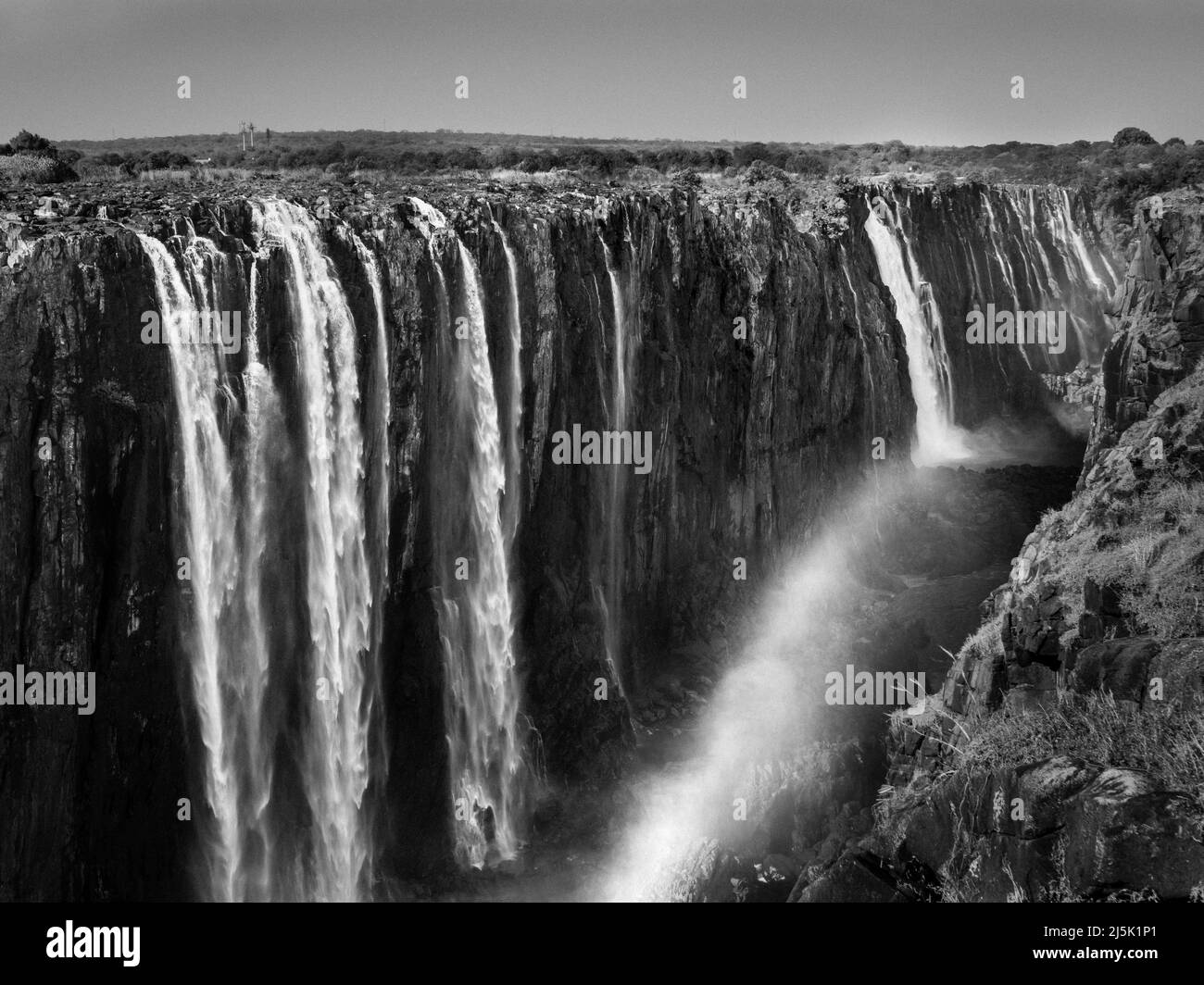 Victoria Falls and Gorge with Rainbow, Zambezi River, between Zimbabwe and Zambia, Africa in Monochrome Black and White Stock Photo
