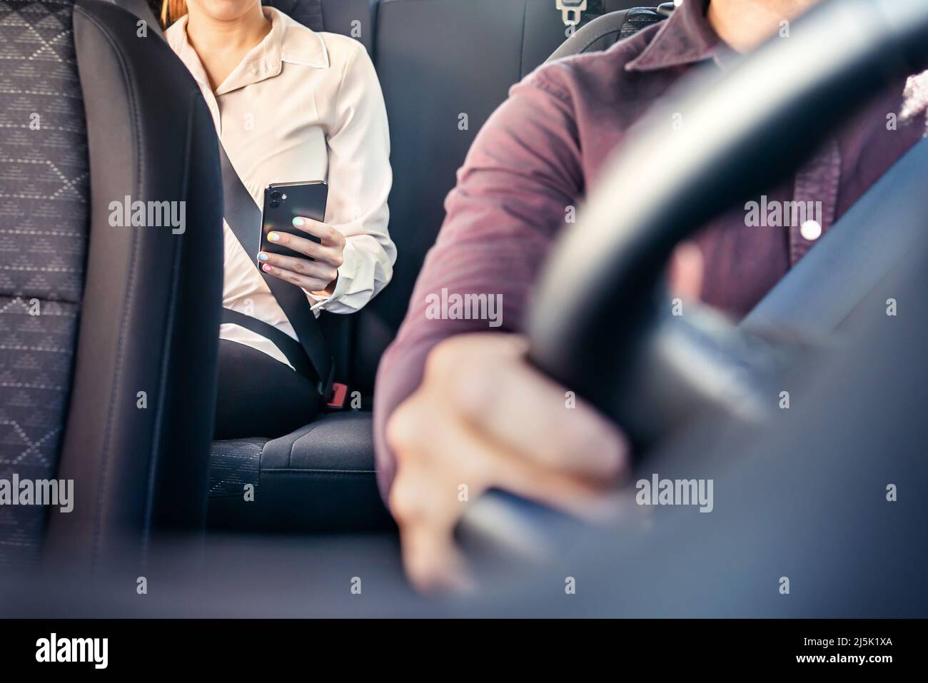 Phone in car or taxi. Passenger woman using cellphone in back seat of cab. Driver and customer. Rideshare mobile app. Professional business person. Stock Photo