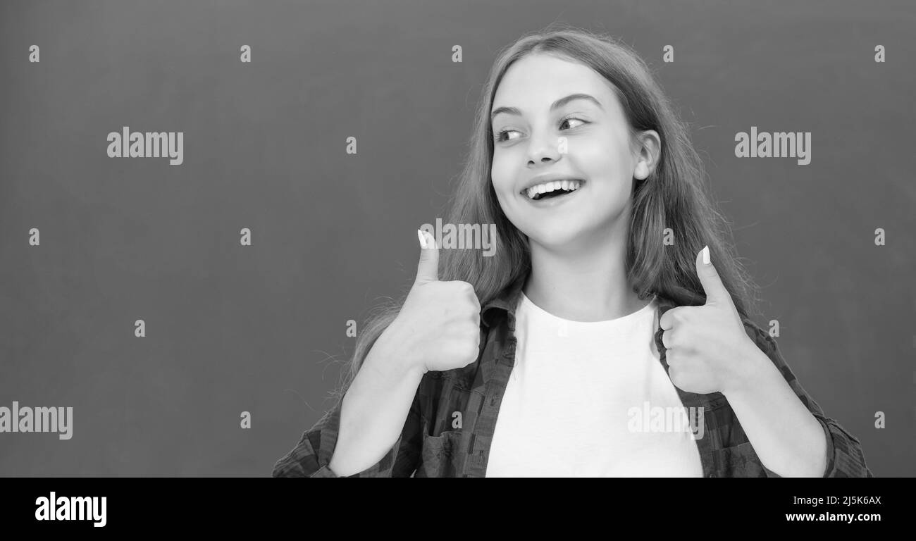 happy teen girl showing thumb up at blackboard, emotions Stock Photo