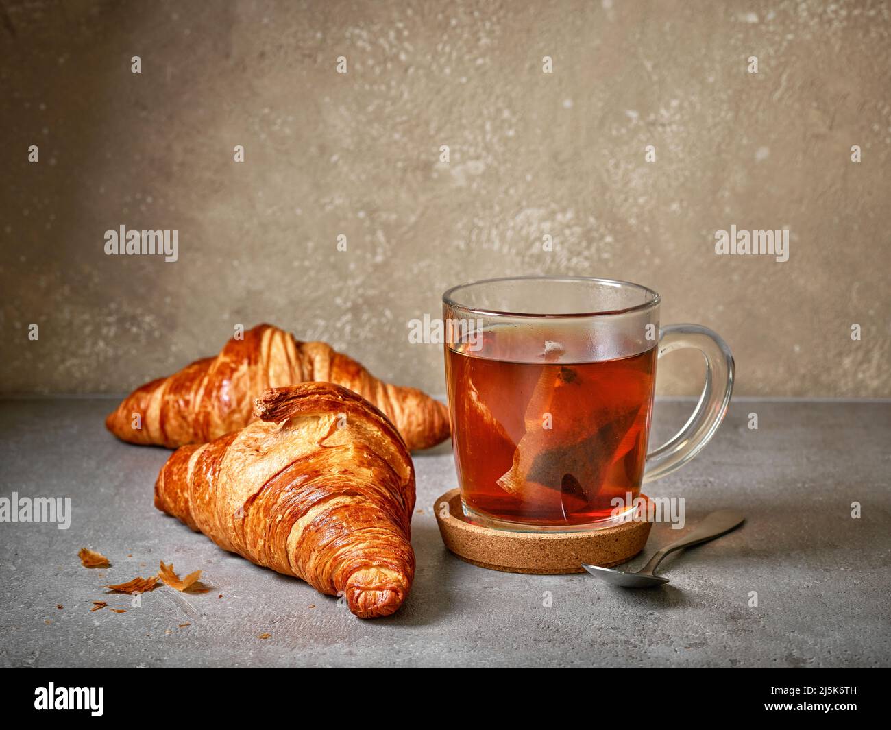 freshly baked croissants and tea cup on grey table Stock Photo